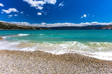 KRK adasındaki Baska 'daki boş çakıl taşı plajı, tatil sezonundan önce Hırvatistan' ın Adriyatik Denizi 'nde masmavi su