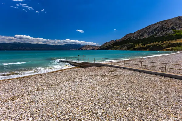 KRK adasındaki Baska 'daki boş çakıl taşı plajı, tatil sezonundan önce Hırvatistan' ın Adriyatik Denizi 'nde masmavi su