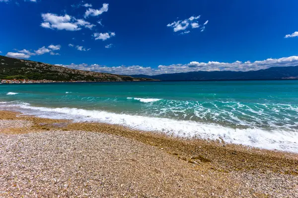 KRK adasındaki Baska 'daki boş çakıl taşı plajı, tatil sezonundan önce Hırvatistan' ın Adriyatik Denizi 'nde masmavi su
