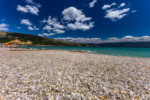 KRK adasındaki Baska 'daki boş çakıl taşı plajı, tatil sezonundan önce Hırvatistan' ın Adriyatik Denizi 'nde masmavi su
