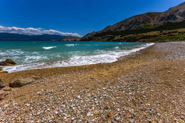 KRK adasındaki Baska 'daki boş çakıl taşı plajı, tatil sezonundan önce Hırvatistan' ın Adriyatik Denizi 'nde masmavi su