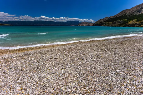 KRK adasındaki Baska 'daki boş çakıl taşı plajı, tatil sezonundan önce Hırvatistan' ın Adriyatik Denizi 'nde masmavi su