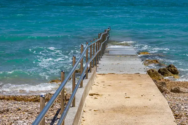 Plaj tekerlekli sandalyede hareket eden engelliler için uyarlandı, Adriyatik Denizi 'ne beton giriş engelliler için koruyucu bir parmaklık ile, 