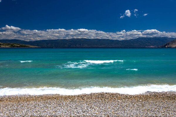 Empty pebble beach in Baska on the island of KRK, azure blue water in the Adriatic Sea, Croatia before the holiday seaso