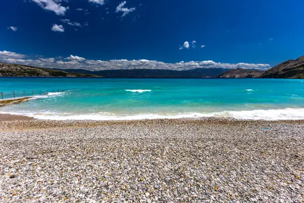 KRK adasındaki Baska 'daki boş çakıl taşı plajı, tatil sezonundan önce Hırvatistan' ın Adriyatik Denizi 'nde masmavi su