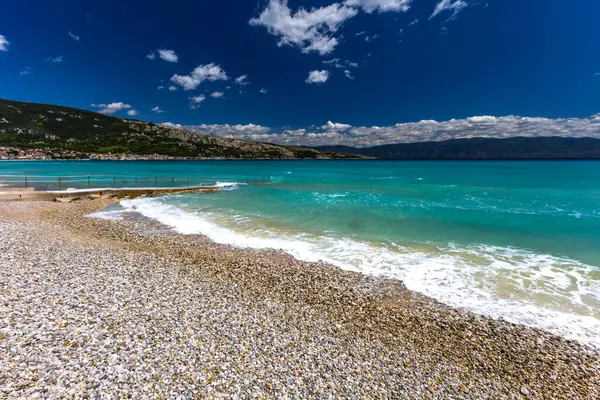 KRK adasındaki Baska 'daki boş çakıl taşı plajı, tatil sezonundan önce Hırvatistan' ın Adriyatik Denizi 'nde masmavi su