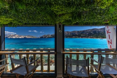 KRK adasındaki Baska körfezindeki gök mavisi suyun manzarası bir restoranın penceresinden, sahil şeridinin ilk hattındaki restoran, Bask 'ın merkezi.