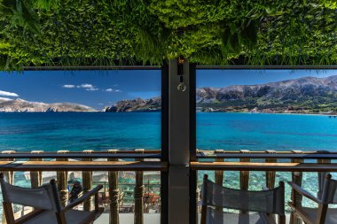 KRK adasındaki Baska körfezindeki gök mavisi suyun manzarası bir restoranın penceresinden, sahil şeridinin ilk hattındaki restoran, Bask 'ın merkezi.