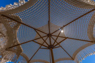 Hırvatistan 'ın KRK adasındaki Adriyatik Denizi kıyısındaki bir meyhanenin verandasında saman şemsiyesi altında sabah kahvesi içmek