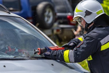 Kurtarma ekibinden bir itfaiyeci bir arabanın ön camını kesti. Araba kazasının olduğu yerde kurtarma operasyonu düzenlemek için özel aletler.