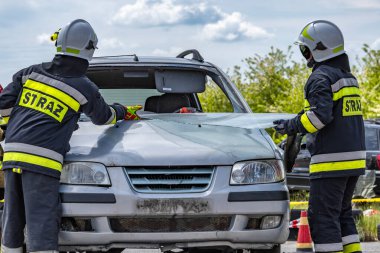Kurtarma ekibinden bir itfaiyeci bir arabanın ön camını kesti. Araba kazasının olduğu yerde kurtarma operasyonu düzenlemek için özel aletler.