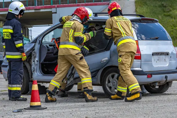 İtfaiyeciler kazadan sonra bir arabanın gövdesini kesiyorlar, bir yolcuyu hurdaya dönmüş arabadan çıkarıyorlar, arabanın kapısını söküyorlar.