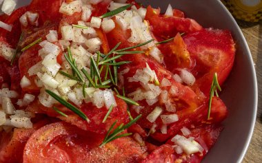 Hırvatistan 'dan gelen zeytinyağı, soğan ve biberiye ile dilimlenmiş taze kırmızı domateslerle dolu bir tabağı kapat,