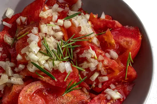 Hırvatistan 'dan gelen zeytinyağı, soğan ve biberiye ile dilimlenmiş taze kırmızı domateslerle dolu bir tabağı kapat,