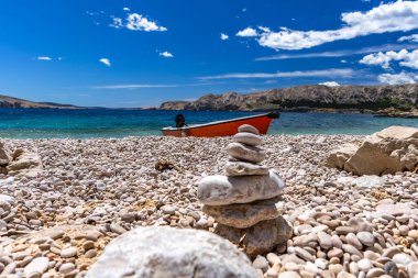 Jablanova Sahili, turuncu balıkçı teknesi, Hırvatistan 'ın KRK adasındaki Adriyatik Denizi ve Velebit Dağları' nın zeminine karşı boş bir plajın kıyısında durdu.