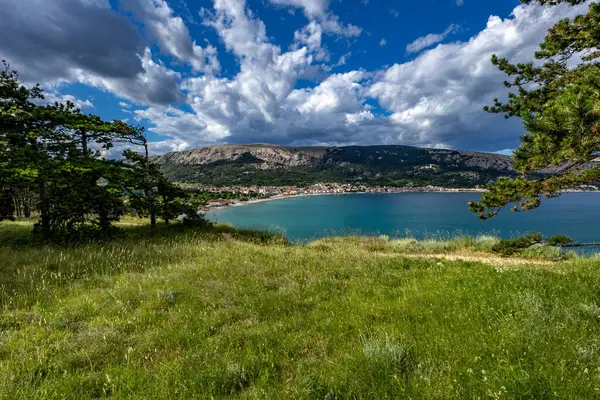 Açıklıkta yeşil çimenler, Baska kasabası yakınlarındaki bir patikada dinlenme, körfez ve şehir manzarası