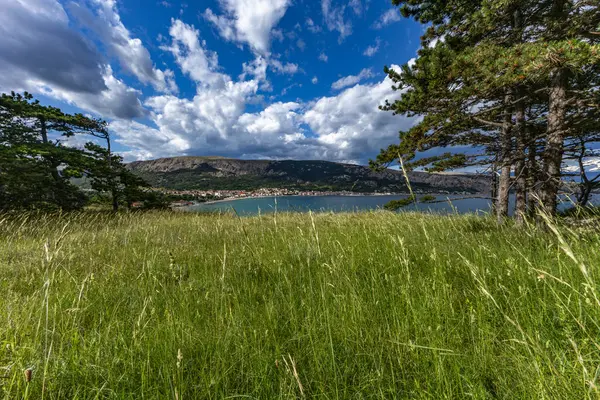 Açıklıkta yeşil çimenler, Baska kasabası yakınlarındaki bir patikada dinlenme, körfez ve şehir manzarası