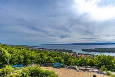 Punat tepesindeki Üç Haç Sığınağı, tapınağa dik kayalık bir yoldan giriş, KRK 'daki Punat kasabasının manzarası.