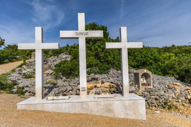 Punat tepesindeki Üç Haç Sığınağı, tapınağa dik kayalık bir yoldan giriş, KRK 'daki Punat kasabasının manzarası.