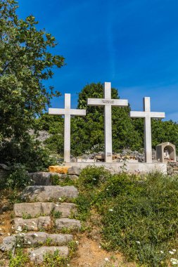 Punat tepesindeki Üç Haç Sığınağı, tapınağa dik kayalık bir yoldan giriş, KRK 'daki Punat kasabasının manzarası.