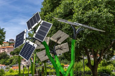 Fotovoltaik paneller, bir çocuğun oyun grubuna güç veren bir ağaca benzeyen metal bir yapının üzerine kurulmuş.