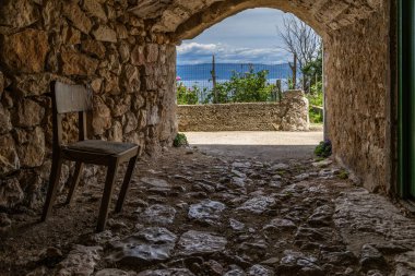 Vrbnik 'teki eski kasabanın duvarlarının altından geçmek, eski ahşap bir sandalye, turistler için dinlenme yeri.