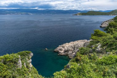 Vrbnik kasabası yakınlarındaki Pebbly Beach Kozica, Adriyatik Denizi kıyısındaki koyu masmavi su, Croati 'deki turizm sezonundan önce insanların olmadığı bir plaj.