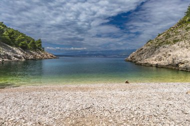 Vrbnik kasabası yakınlarındaki Pebbly Beach Kozica, Adriyatik Denizi kıyısındaki koyu masmavi su, Croati 'deki turizm sezonundan önce insanların olmadığı bir plaj.