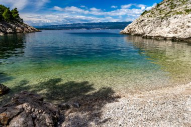 Vrbnik kasabası yakınlarındaki Pebbly Beach Kozica, Adriyatik Denizi kıyısındaki koyu masmavi su, Croati 'deki turizm sezonundan önce insanların olmadığı bir plaj.