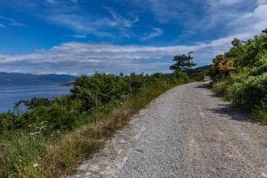 Vrbnik kasabası yakınlarındaki Pebbly Beach Kozica, Adriyatik Denizi kıyısındaki koyu masmavi su, Croati 'deki turizm sezonundan önce insanların olmadığı bir plaj.