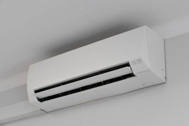 Tavandan sarkan klima beyaz bir duvarda, hasarlı klima.