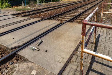 Rayların yanındaki yeşil spor ayakkabılar, yaya geçidinde raylara çarpan biri, korumasız bir demiryolu geçidi, bir intihar kendini trenin altına attı.