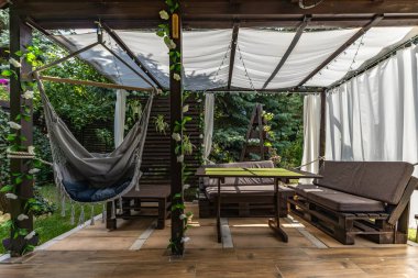 Sallanan hamak, verandada asılı gri Brezilya sandalyesi ahşap pergola, bahçede dinlenmek için bir yer.