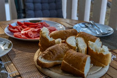 Taze dilimlenmiş ekmek, kırmızı olgun domates, apartmanın önündeki terasta Akdeniz kahvaltısı, beslenme yemeği.