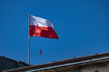 Polonya Cumhuriyeti 'nin ulusal bayrağı bir kamu binasının çatısında dalgalanan beyaz ve kırmızı bayrak