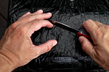 Siyah bir bıçakla paketlenmiş paketi açmak, sevkiyatı açmak.