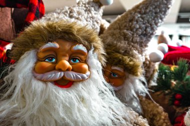 Beyaz sakallı ve tüylü şapkalı dekoratif Noel Baba heykelciklerinin yakın çekimi. Sıcak ışıklandırmalı ve neşeli ruhlu Noel tatili atmosferi.