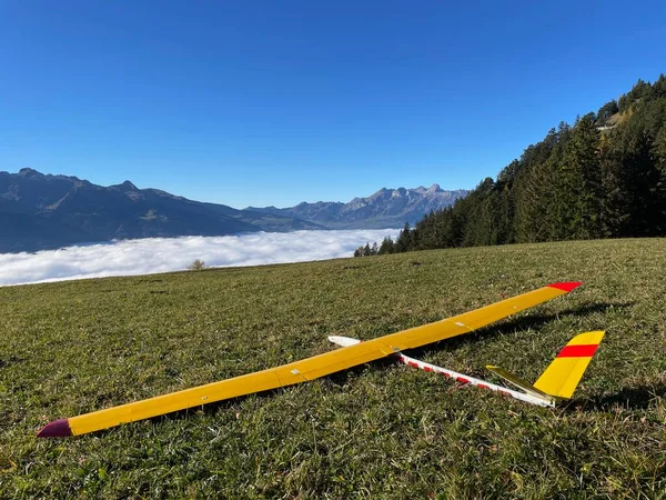 Close up of yellow model airplane laying in grass, Triesenberg, Liechtenstein. Foggy Rhine valley in the background. High quality photo