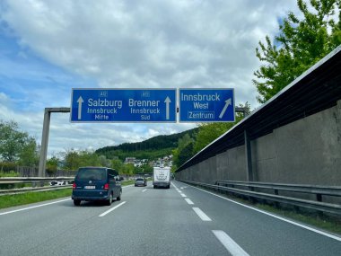 Austrian highway with road sign indicating Salzburg, Brenner, Innsbruck. Innsbruck, Austria, 12.05.2023. High quality photo clipart
