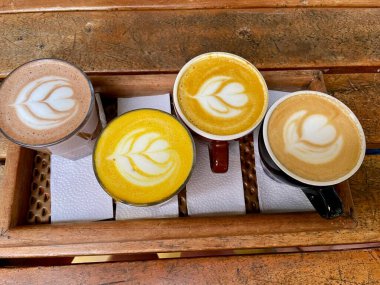 Farklı sıcak içeceklerin havadan görünüşü - sıcak çikolata, Matcha çayı, kahve, cappuccino leche dorada - ahşap masadaki güzel latte sanatı. Yüksek kalite fotoğraf.