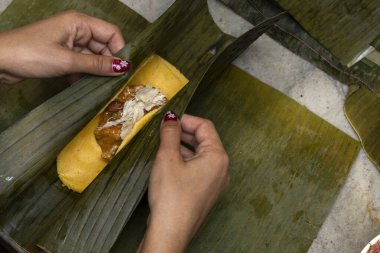 Preparation and ingredients of a Hallaca or tamale wrapped in banana leaf clipart