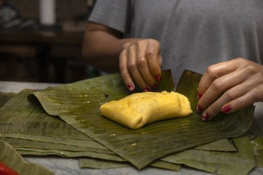 wrap a Hallaca or tamale in banana leaf. clipart
