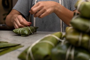 Kadının elleri hallaka ya da muz yaprağına tamale bağlıyor. Geleneksel yemek.