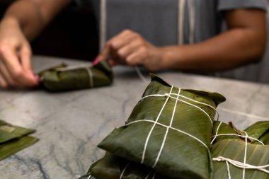 Kadının elleri hallaka ya da muz yaprağına tamale bağlıyor. Geleneksel yemek.