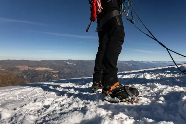 Karda tırmanma kramponları ve kar tırmanışı için güvenlik ekipmanları olan bir adamın en üst görüntüsü.