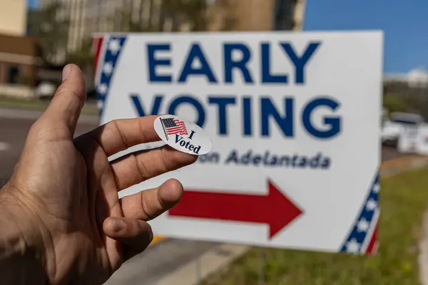 Elinde oy verdiğimi söyleyen bir çıkartma var. Halka açık yol erken seçimlerinde bir reklam panosunun arka planında. Kavramsal fotoğraf