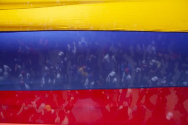 Venezuela bayrağının şeffaflığından görünen bir kalabalık. Birlik ve sivil ifadenin sembolü..