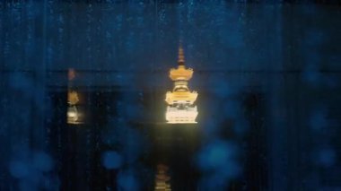 Aydınlatılmış pagoda Yağmurlu pencere camlarından yansıyor