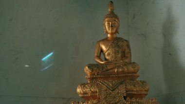 Altın Buda heykeli mermer duvarda duruyor.