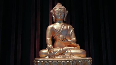Koyu arkaplanda duran altın Buda heykeli